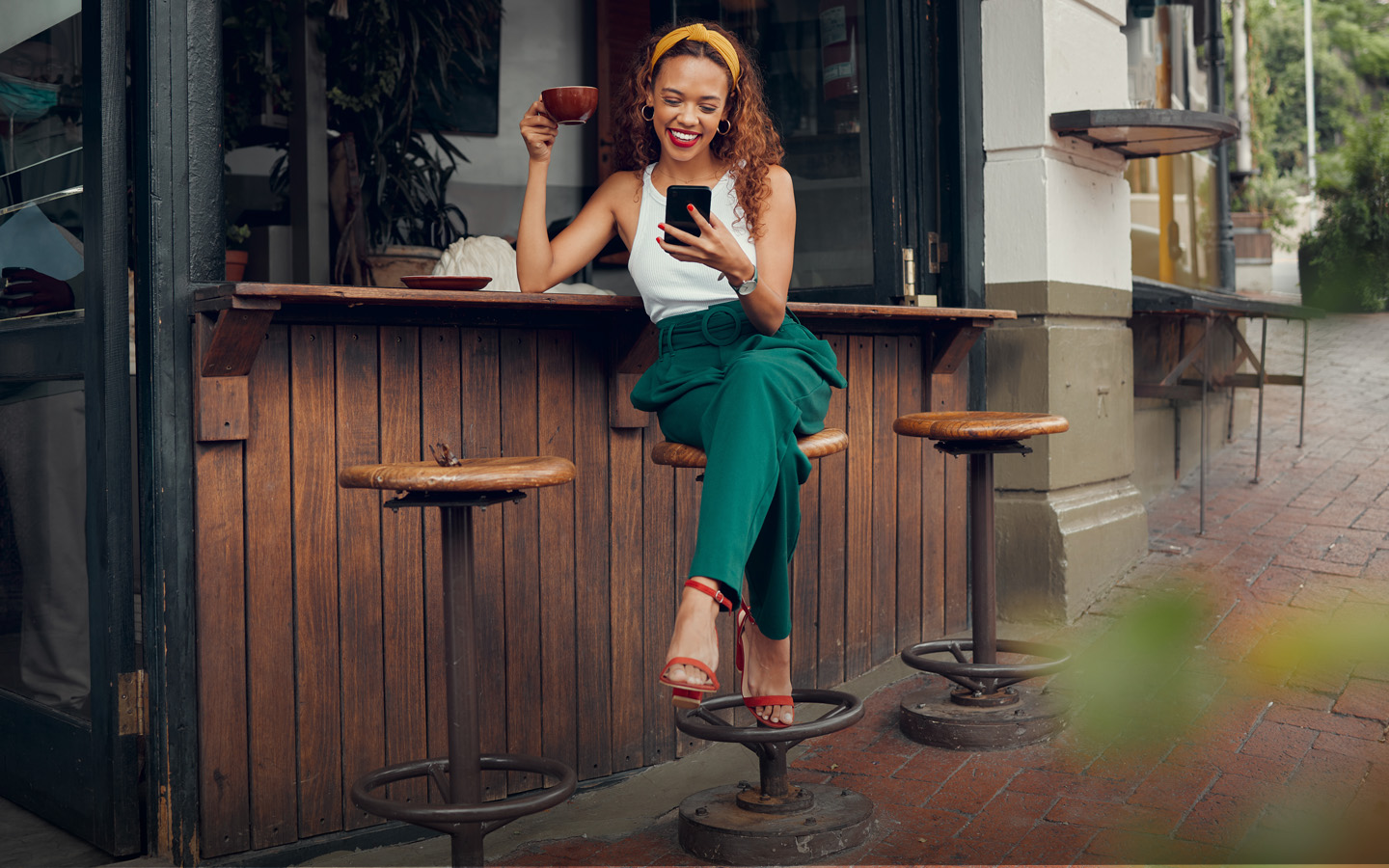 Phone, social media and coffee with a black woman customer at a cafe counter on the sidewalk. Coffee shop, internet and communication with a young female typing a text message in a restaurant